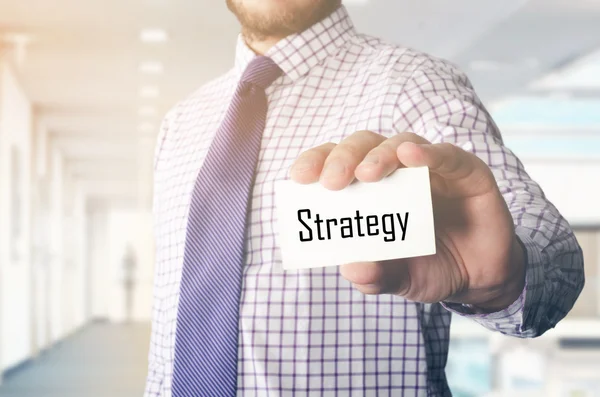 Hombre de negocios en la oficina mostrando tarjeta con texto: Estrategia — Foto de Stock