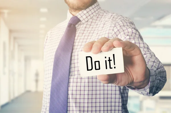 Biznesmen w biurze pokazujący kartę z tekstem: Zrób to ! — Zdjęcie stockowe