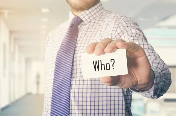Επιχειρηματίας στο γραφείο που δείχνει κάρτα με κείμενο: Ποιος ? — Φωτογραφία Αρχείου