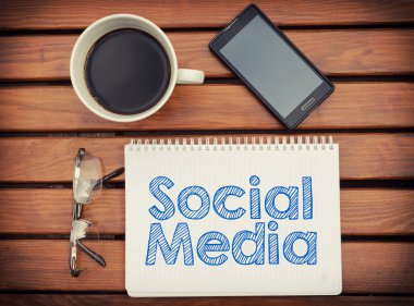 Kahve, cep telefonu ile tabloda sosyal medya içindeki metin ile defter