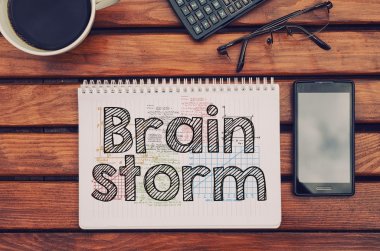 Defter metin ile beyin fırtınası içinde kahve, cep telefonu ve hesap makinesi ile masada