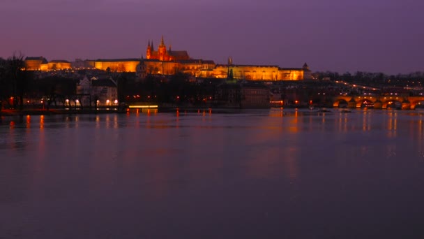 Timuplynulý široký statický záběr řeky Vltavy a Pražského hradu za soumraku