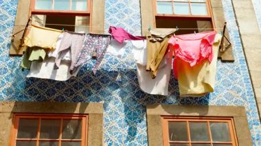 Porto, Portekiz 'in manzaralı sokaklarına yerel yetenekler katarak büyüleyici fayanslı bir evin önünde asılı duran renkli kıyafetler, Porto şarabıyla ünlüdür.