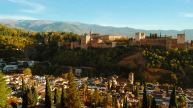 Güneş batarken, Alhambra Sarayı ve Granada, Endülüs, İspanya 'nın Eski Mahallesi sıcak renklerle yıkanarak çarpıcı bir manzara yaratıyor.