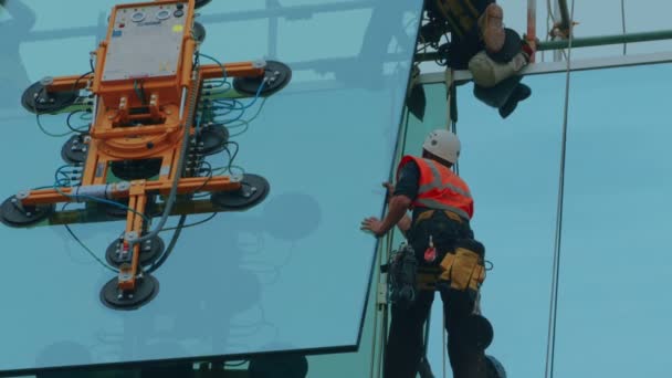 Primer plano del grupo de constructores asegurando un panel de vidrio en su lugar — Vídeos de Stock