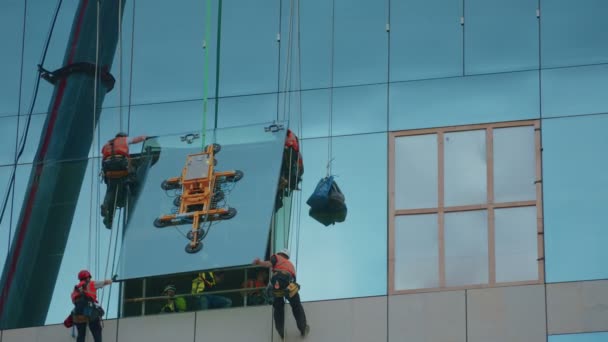 Ampio timelapse di gruppo di costruttori che fissano un pannello di vetro in posizione — Video Stock