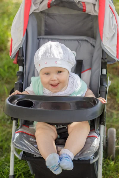 Little girl sitting in a baby carriage — Stock Photo, Image