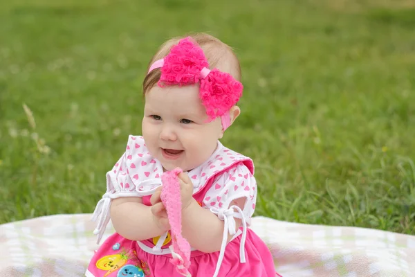 Маленькая новорожденная девочка сидит на траве — стоковое фото