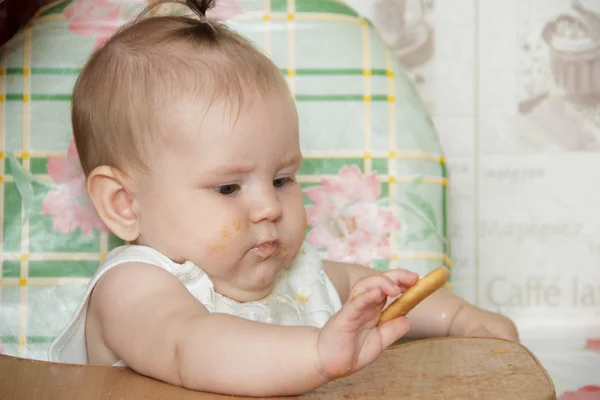 女の子子供ハイチェアに座っているし、クッキーを食べる — ストック写真