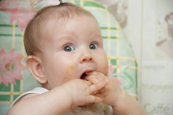 Niña pequeña se sienta en una trona y come galletas — Foto de Stock