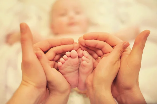 Pieds de petits enfants dans les mains des parents — Photo