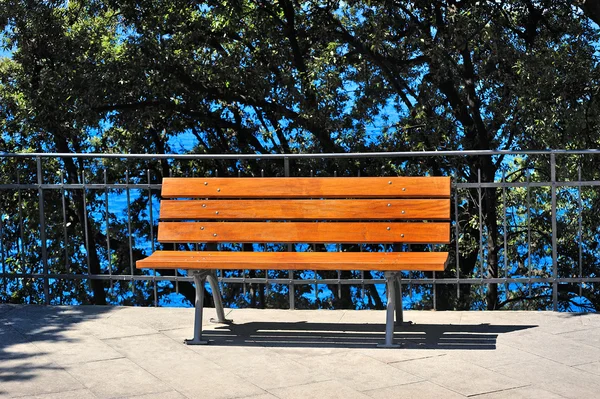 Güneşli bir parkta suya yakın tezgah — Stok fotoğraf