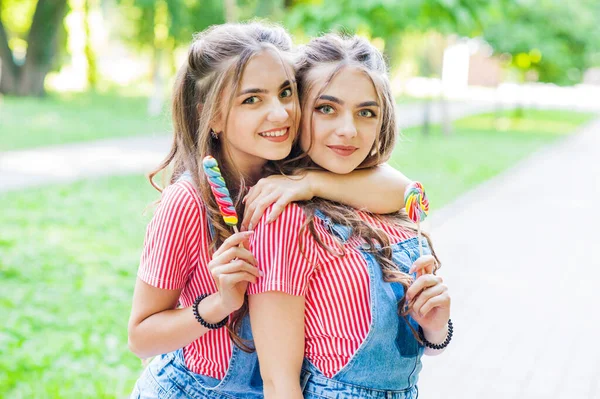 Duas Meninas Gêmeas Bonitas Abraçando Macacão Jeans Com Pirulitos — Fotografia de Stock