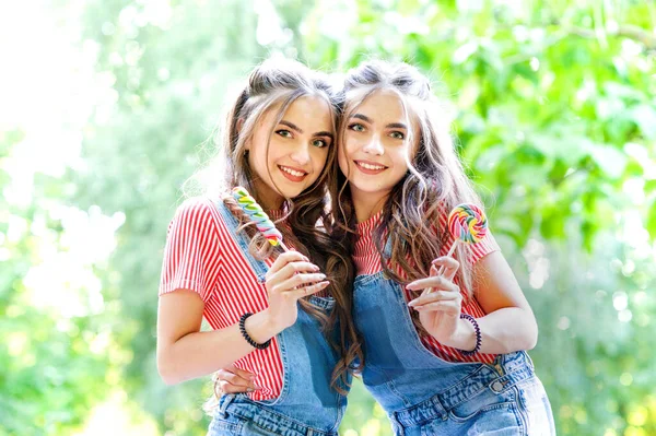 Duas Meninas Gêmeas Bonitas Abraçando Rindo Macacões Jeans Com Pirulitos — Fotografia de Stock