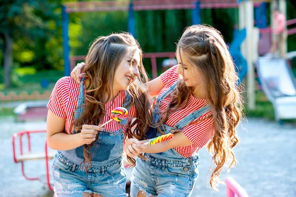 Duas Irmãs Gêmeas Felizes Rindo Macacão Jeans Com Pirulitos Parque — Fotografia de Stock