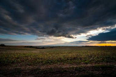 dramatic dark storm sky with clouds at sunset over the field after harvest