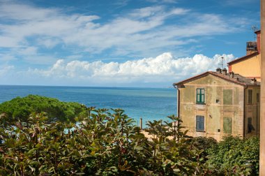 Akdeniz kıyısında eskimiş bir cephesi ve yeşil kepenkleri olan bir ev.