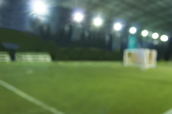 Campo de entrenamiento de fútbol de estilo borroso con jugadores por la noche — Foto de Stock