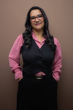 Uzun gri saçlı, gözlüklü, elleri ceplerinde gülümseyen arkadaş canlısı bir kadın. Dikey stüdyo portresi kadınlık için ideal, olgun bayan, kilise ve dini etkinlikler için resmi kıyafet.