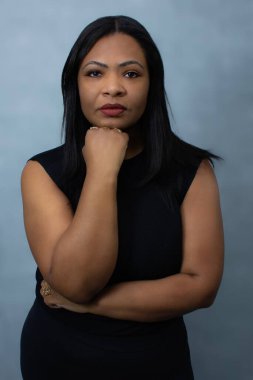 Eli çenesinde olan yakışıklı Brezilyalı siyahi kadın ciddi ve kendinden emin bir ifadeyle kameraya bakıyor. Belden yukarı stüdyo portresi özgüven, güven ve kadın güçlendirme kavramları için idealdir..