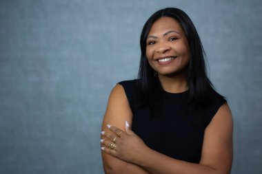 Kollarını kavuşturmuş, gülümseyen ve kameraya bakan güzel Brezilyalı siyahi kadın. Fotokopi alanı olan yatay stüdyo portresi güzellik, güven, güçlendirme ve kadınsı reklamlar için mükemmel..