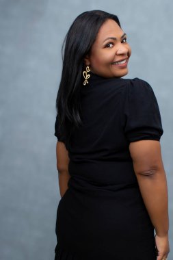 Güzel ve iri yapılı kahverengi tenli bir kadın nazikçe omzunun üstünden bakıyor. Fotokopi alanı olan orta boy bir stüdyo, vücut pozitifliği, bireysellik, çeşitli güzellik ve kadınsı kendine güven kavramları için ideal..