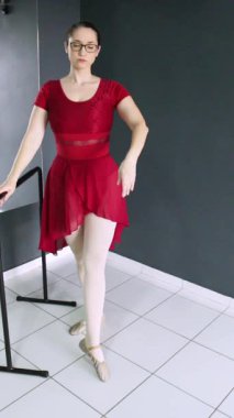 Balerin barın yanında tendu ve rond de jambe terre gösterisi yapıyor. Dikey video dans dersleri, bale dersleri, dans dersleri ve yeni başlayanlar için harika.