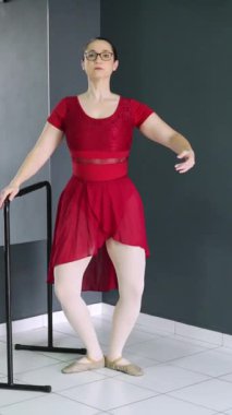 Balerin barın yanında pli, elev ve grand pli gösterisi yapıyor. Dansçılar için dikey video ideal, acemi bale öğretmeni, dans öğrencisi ve sosyal medyada dans dersi.