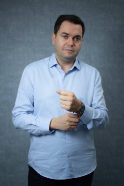 Ofisteki işadamı işe gitmek için hazırlanıyor, gömleğinin düğmelerini ilikliyor. Mavi arka planda fotokopi alanı olan bir stüdyo portresi, kurumsal iş, kariyer, ofis işi, istihdam için ideal.