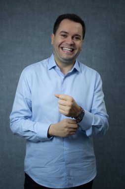 İş adamı iş kıyafetleri içinde gülümsüyor işe hazırlanıyor, gömleğinin düğmelerini ilikliyor. Kopya alanı olan dikey stüdyo portresi, şirket işi, kariyer, ofis işi, istihdam için ideal.