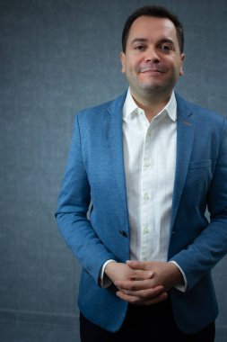 İşletme müdürü ellerini sıkarak sakince gülümsüyor. Yanal kopyalama alanı olan stüdyo portresi, kurumsal yönetim, insan kaynakları alımı ve dostane çalışma ortamı için ideal.