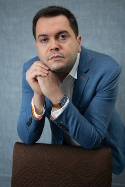 İşadamı dik dik bakıyor ve çenesini sımsıkı elleriyle dinlendiriyor. Şirket işleri, kariyer planlaması, ofis işleri ve istihdam için stüdyo portresi ideal.