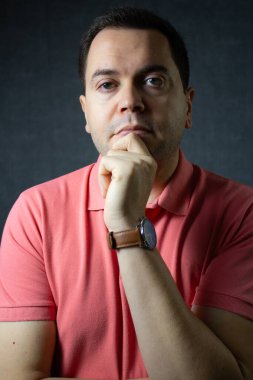 Ciddi orta yaşlı bir adamın portresi, elleri çenesinde. Planlama, tefekkür ve öz farkındalık için harika. Dramatik ışıklandırmayla çekilen dikey stüdyo.