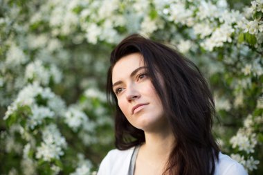 Genç güzel esmer kadın çiçek açan elma ağacı bahçede
