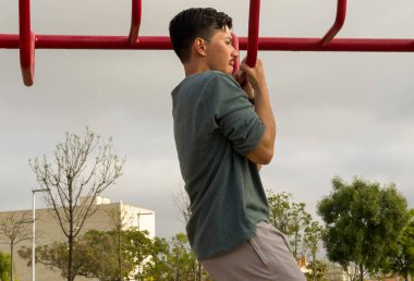 Yetişkin bir adam açık hava parkında egzersiz çubuklarında antrenman yapıyor. Fotokopi alanı olan spor görüntüsü, sağlık, spor ve aktif yaşam tarzı konuları için idealdir