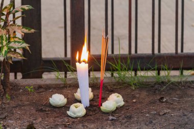 Mum ve tütsü alevi. Dini tören için toprak altında nilüfer var.