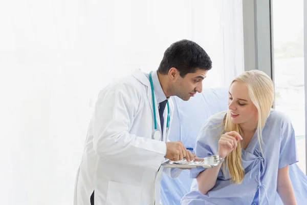 male doctor is bringing medicine to a female patient to eat in a hospital room on day time