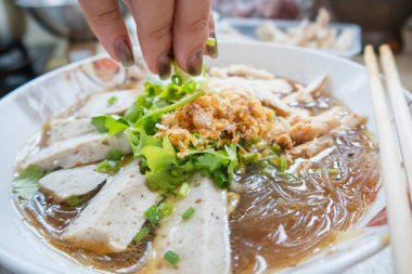 Sebzeli beyaz domuz sosisi ile kaynatılmış vermicelli; mutfakta yemek çubuklarıyla serpiştirilmiş bir kase.