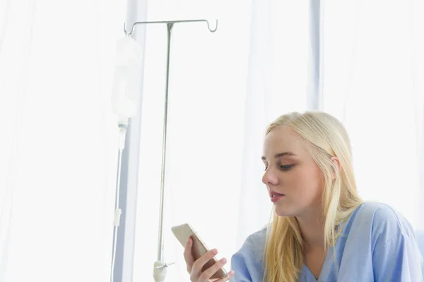 stock image female patient holds the phone on the bed, the patient in the hospital room on day time