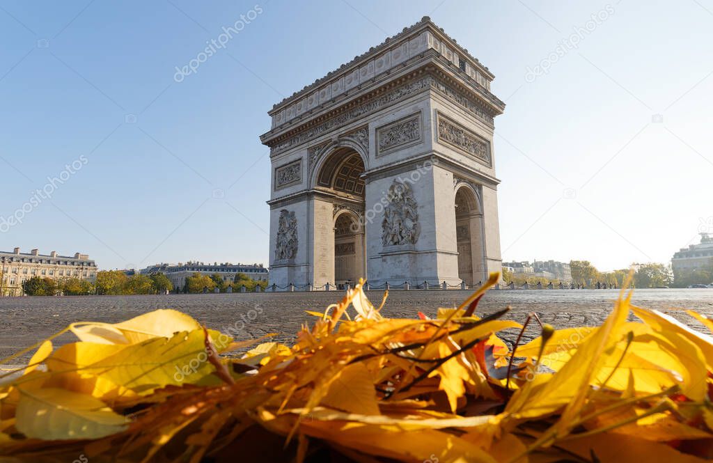 The famous Triumphal Arch and autumnal colorful leaves in the foreground at sunny day , Paris, France.