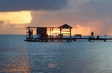 Siluet balıkçısının ahşap kulübesi deniz suyunun üzerinde, günbatımı gökyüzü arka planında, Martinique adasında. Fransız Batı Hint Adaları.