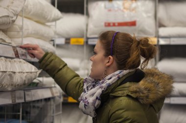 Güzel genç kadın bir mobilya mağazasında yastıklar seçin