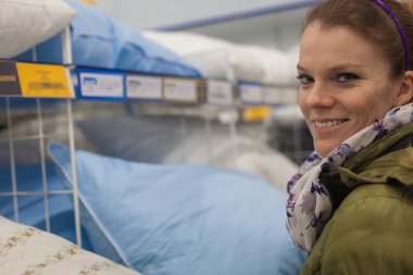 Güzel genç kadın bir mobilya mağazasında yastıklar seçin