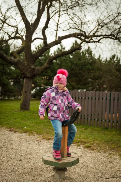 Small girl having fun on the children's attractions in the park — Stock Photo, Image