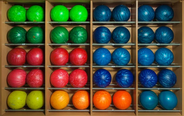 Bowling topları rafta, boyut ve renge göre sıralanmış.