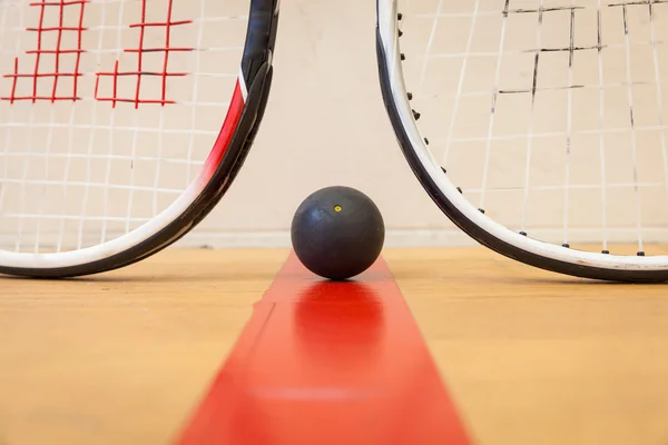 Squash bal tussen twee squash rackets op de rechtbank — Stockfoto