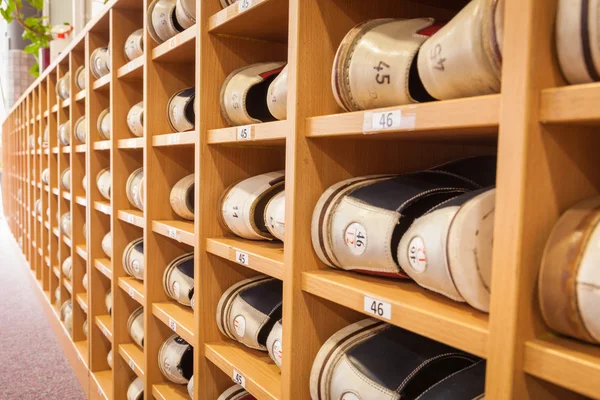 Bowling shoes in a shoe cabinet sorted by size