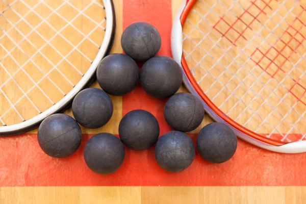 Squash ballen tussen twee squash rackets op de rechtbank — Stockfoto