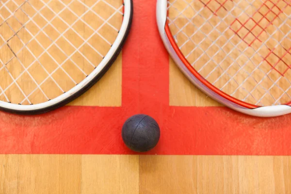 Squash bal tussen twee squash rackets op de rechtbank — Stockfoto