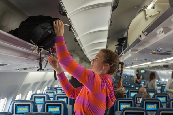 The young girl placed her hand luggage into the compartment on t — Stock Photo, Image